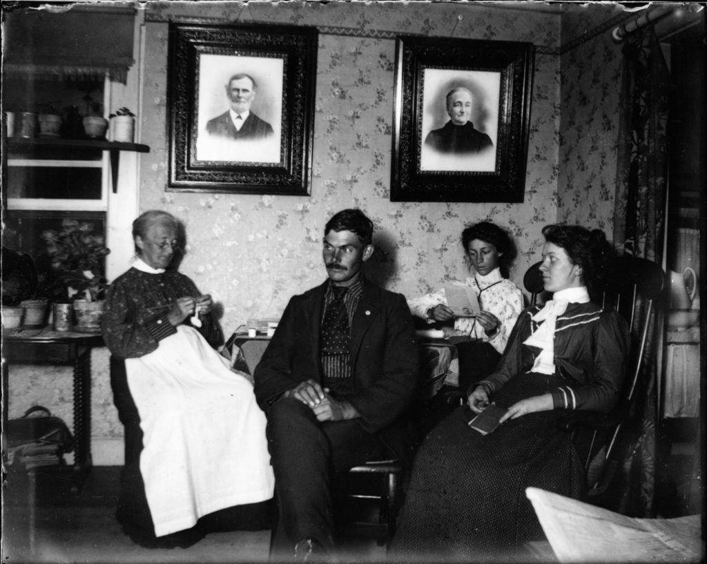 Miniature of Family seated insde a house reading and knitting.