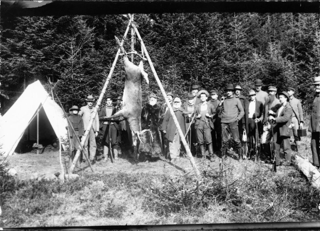 Miniature of Deer hanging upside down surrounded by hunters